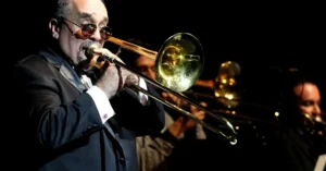 Willie Colón en el escenario, con micrófono en mano y luces de fondo